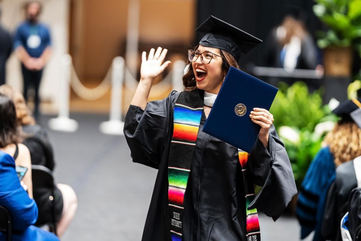 woman holding degree smiling and waving