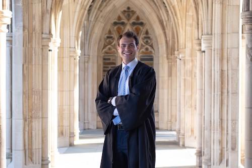 Man smiling while wearing graduation gown