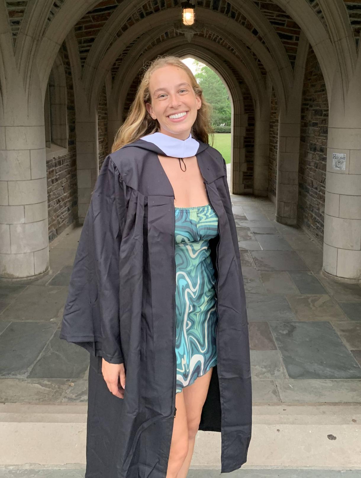 Woman, graduation gown, posing near Duke arches