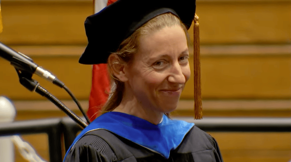 Woman, small smile, wearing cap and gown