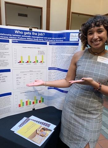 woman posing with her honors thesis presentation