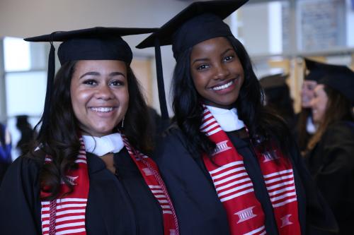 two women in graduation robes and caps smiling