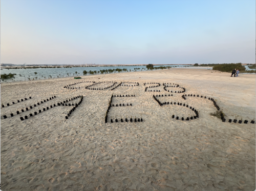 'COP'28 UA E 52" written out on a sandy beach in Dubai