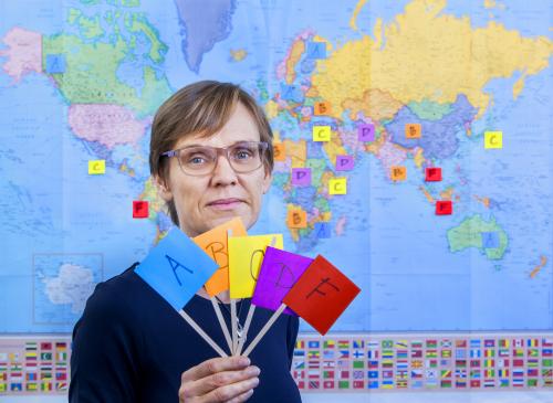 Woman in front of map, holding flags that say A,B,C,D